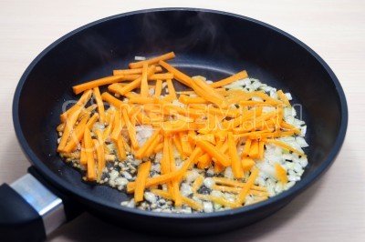На сковороде обжарить, помешивая, мелко нашинкованный лук и соломкой нарезанную морковь 2-3 минуты.